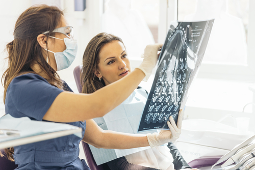 dentist reviews x-ray with female patient