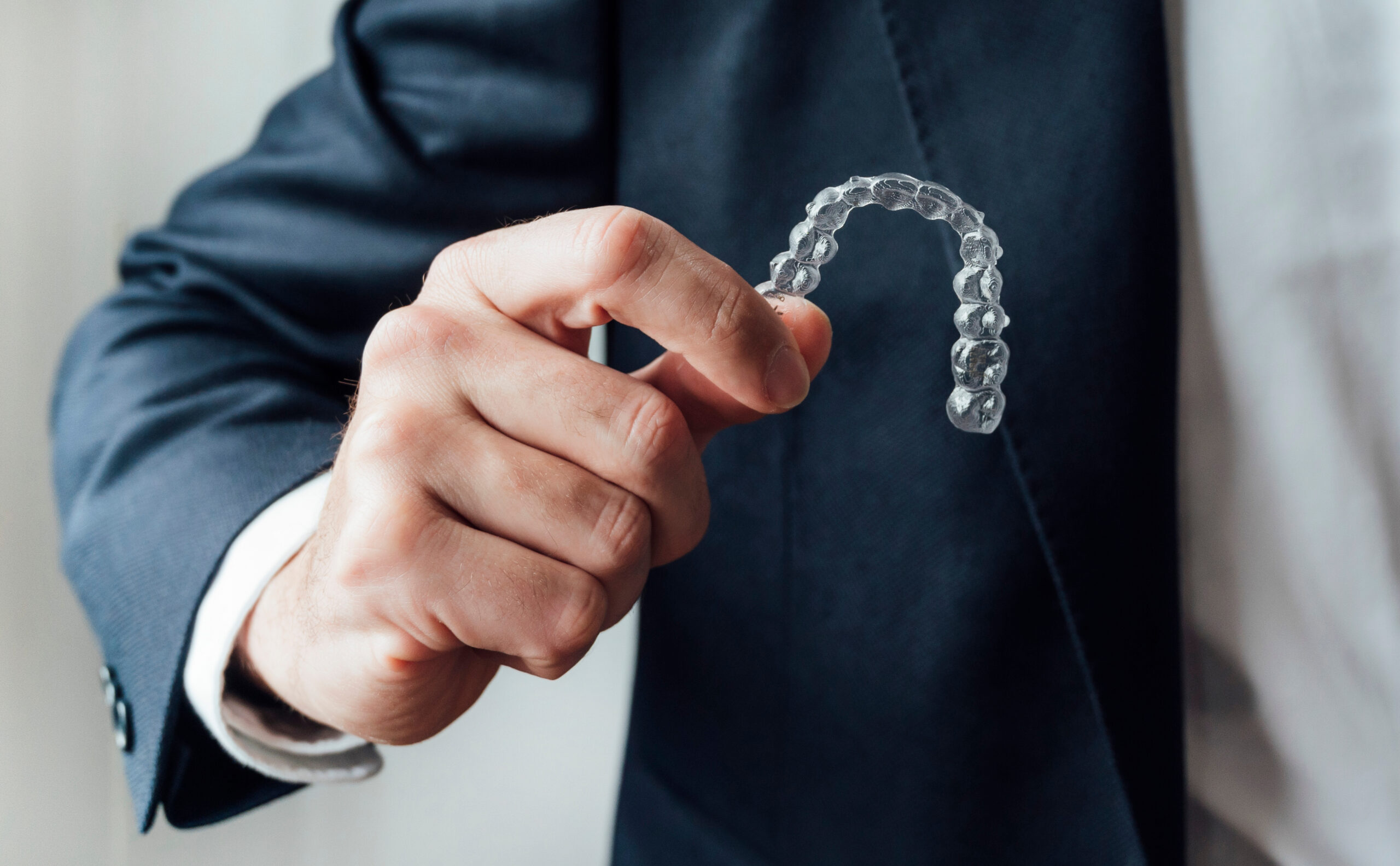 closeup of business man holding out his clear aligners